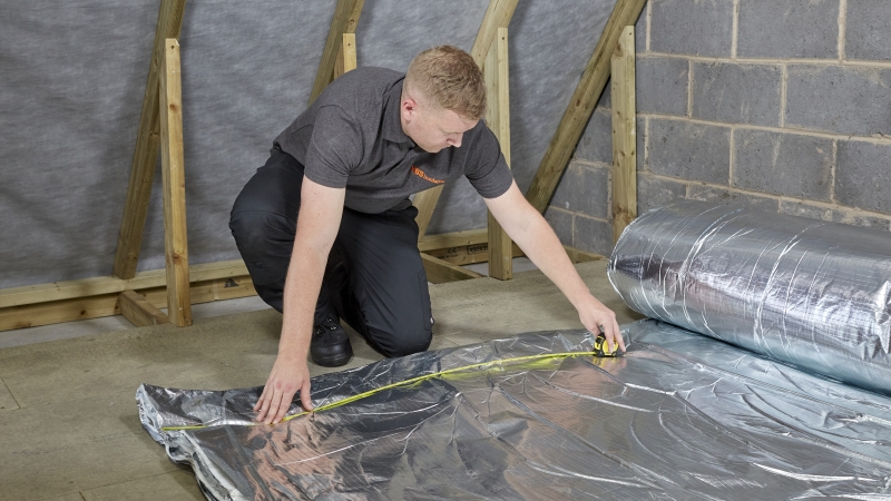 Man lays out YBS Insulation roll in a roof ready to be insulated