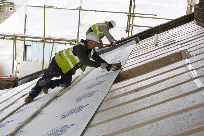 Two installers are working on a roof