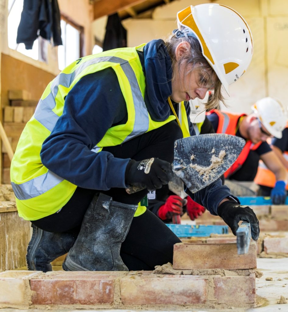 Image shows apprentice in a classroom practicing bricklaying