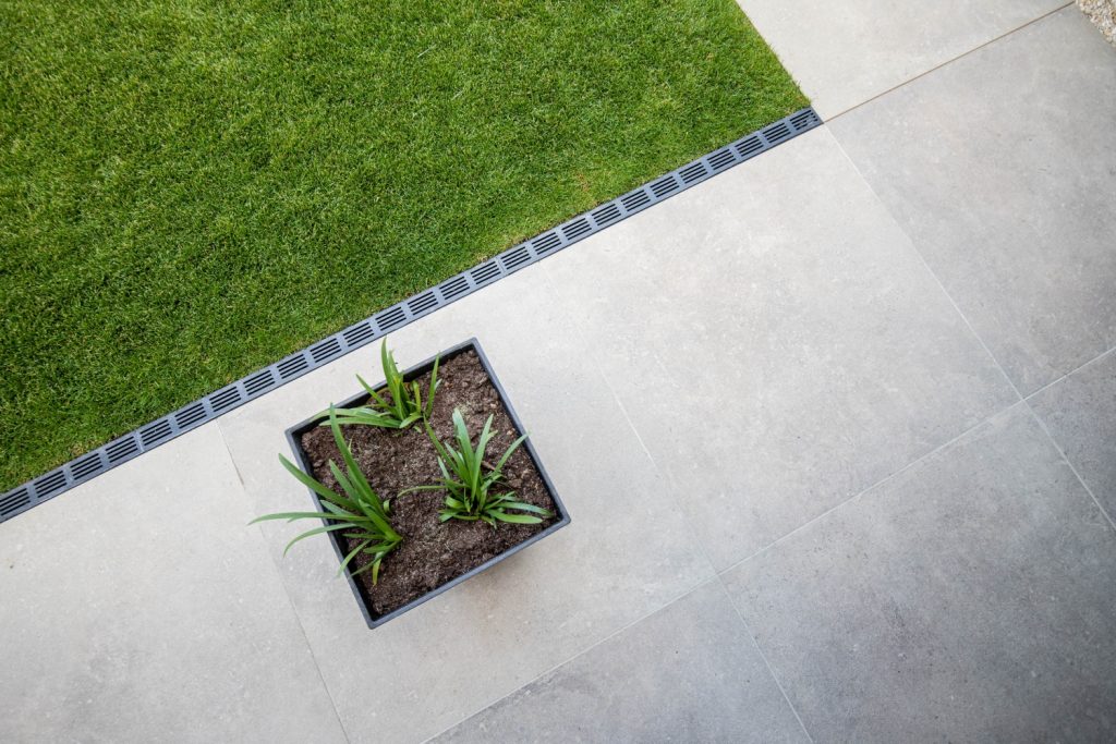 Aerial view shows drainage being used to border a patio moving on to grass in a garden
