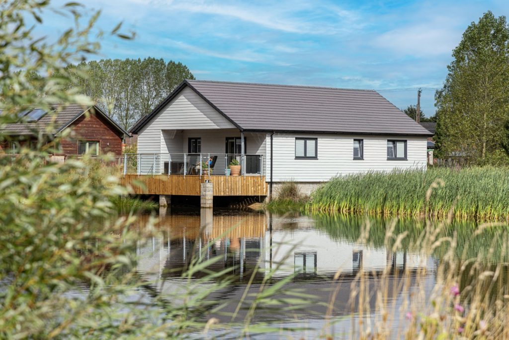Domestic building clad in Marley's white fibre cement cladding in front of lake and trees