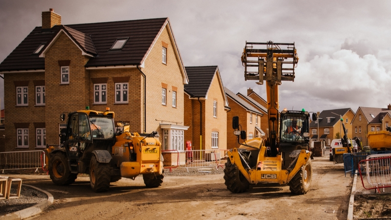 Image of building site of new build homes with plant machinery in the foreground