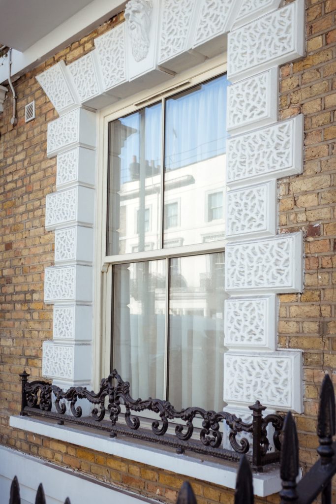 Heritage style sash window with intricate brickwork surround and railings.