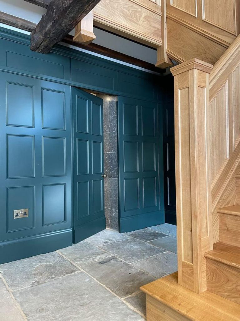 A natural stone tile hallway with ornate green doors and stairway